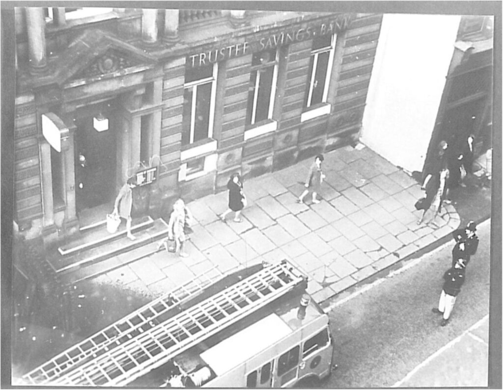 A photograph capturing an evacuation of the building clearly showing the name has changed to The Trustee Savings Bank