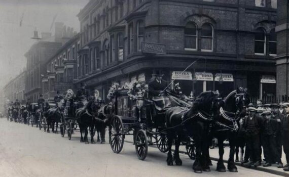 A horse-drawn carriage in a funeral cortege at Free Methodist Church, with Georgian properties and Victoria Building in the background.