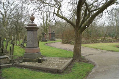 The image shows a cemetery with a tree in the foreground and a pathway leading into the cemetery